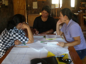 three people gather at one end of a table, looking deep in thought